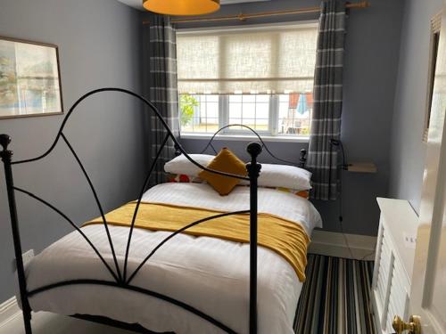 a bedroom with a bed with a yellow blanket and a window at Oakville Entire House in Bray