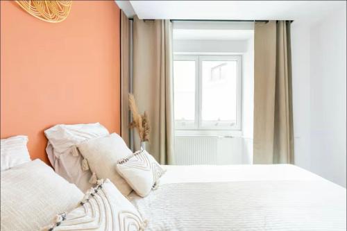 a bedroom with orange walls and a bed with white pillows at General Suite - Strasbourg Hyper Centre in Strasbourg