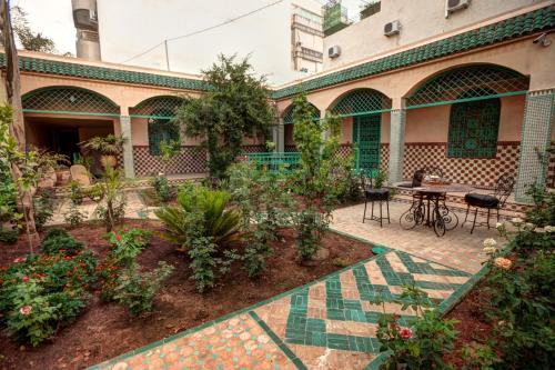 a garden in front of a building with a table and chairs at Riad Dar Ziryab in Fès