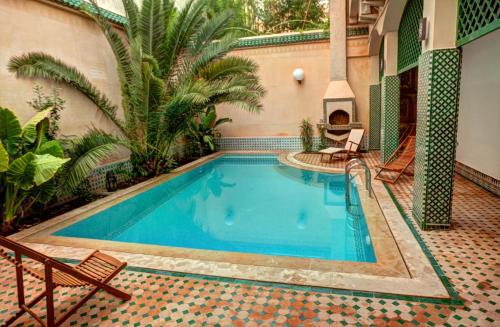 a swimming pool in a courtyard with two chairs at Riad Dar Ziryab in Fez