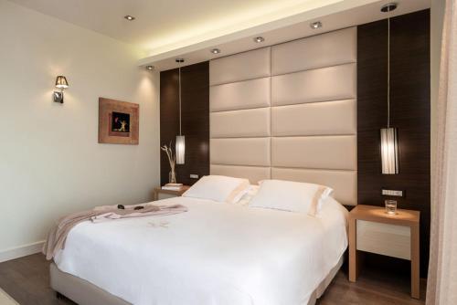 a bedroom with a large white bed with a large headboard at Cretan Dream Resort & Spa in Stalos