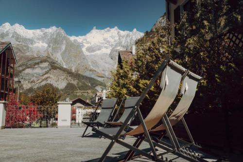 a row of chairs sitting in front of a mountain at Villa Novecento Romantic Hotel - Estella Hotel Collection & Experience in Courmayeur