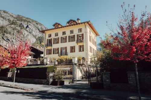 a large white building with red trees in front of it at Villa Novecento Romantic Hotel - Estella Hotel Collection & Experience in Courmayeur