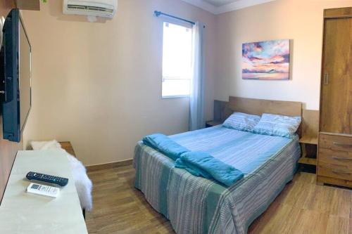 a bedroom with a bed with blue sheets and a window at Casa Sauê in Aracruz