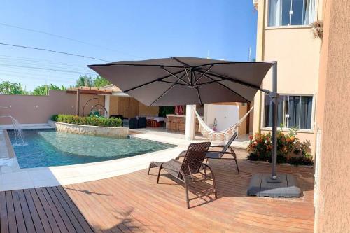 a patio with a hammock and an umbrella next to a pool at Casa Sauê in Aracruz