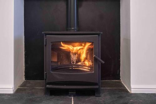 a stove with a fire in it in a room at Hycemoor Escape-Private Hot tub in Corney