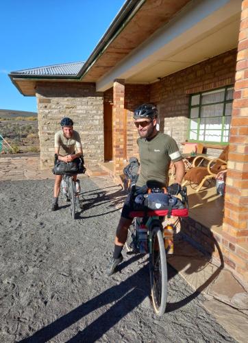 two men on bikes parked outside a house at Oupoort Eco & Guest Farm - Sutherland - Middelpos in Sutherland