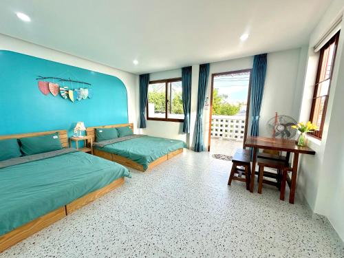 a bedroom with two beds and a desk and windows at NẮNG Homestay - Làng Chài Mũi Né - Mui Ne Fishing Village in Mui Ne