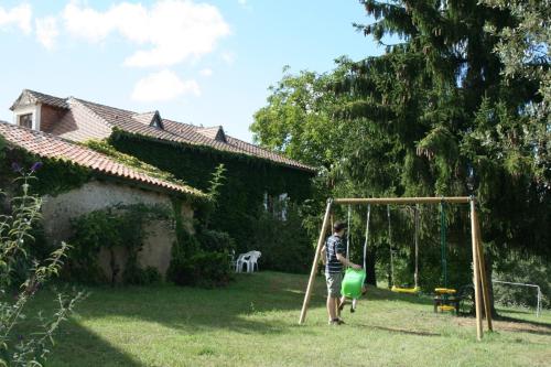a man is playing on a swing set in a yard at Dordogne Le Grand Gîte du Pautys au Cœur du Périgord Vert proche Brantôme in Sorges