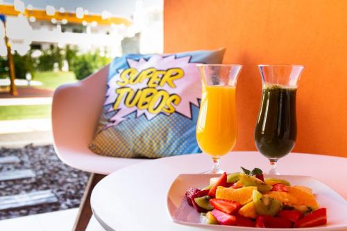 un tavolo con un piatto di cibo e due bicchieri di succo di RIDE Surf Resort & Spa Peniche a Peniche