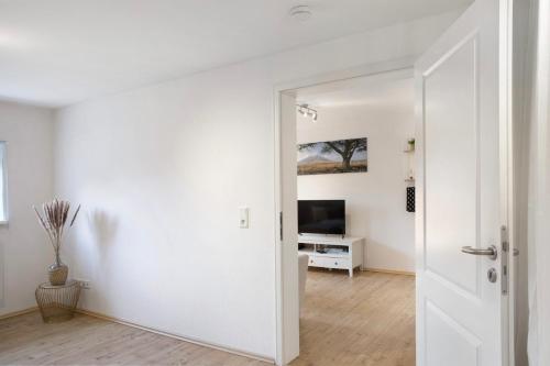 a white room with a door and a television at Alsfelder Wein-Suite in Alsfeld