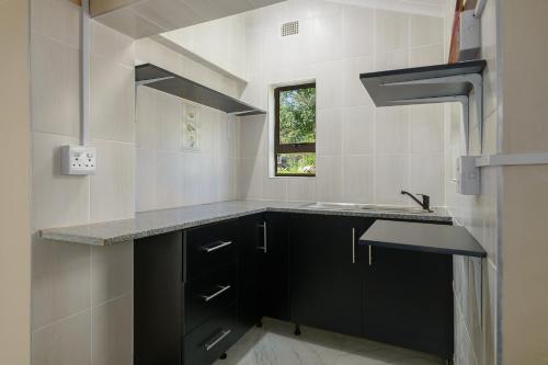 a kitchen with black cabinets and a sink at Resthaven in Margate