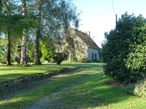 a path leading to a stone house with trees at La Crepelliere in Villedieu-les-Poëles
