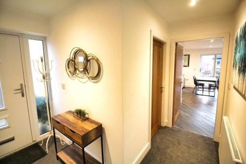 a hallway with a table and a mirror on a wall at 2 Bed Bungalow - Parking - New Build - High End Furnishings - Wheel Chair Accessible - Large Enclosed Garden - Dog Friendly in Rotherham