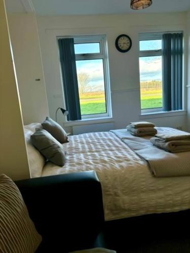 a bedroom with a large bed and two windows at Modern apartment in Stenhousemuir in Stenhousemuir