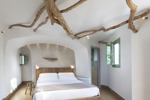 a bedroom with a large bed with a wooden headboard at Gallicantu Stazzo Retreat in Luogosanto