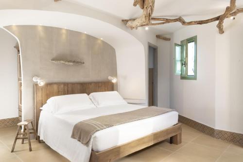 a bedroom with a large bed with a wooden headboard at Gallicantu Stazzo Retreat in Luogosanto