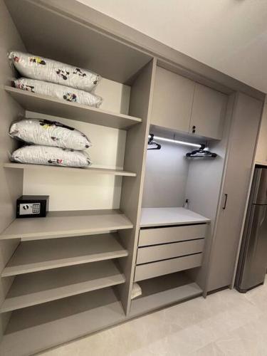 a walk in closet with white shelves and pillows at Apto com piscina aquecida perto do mar in Bombinhas
