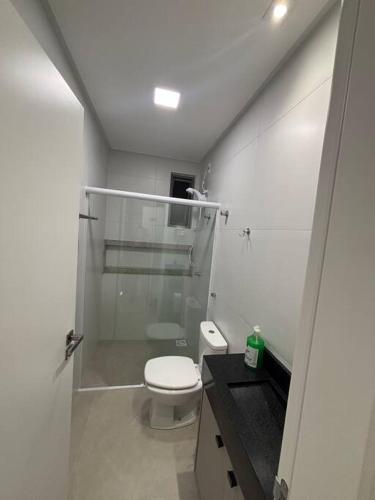 a white bathroom with a shower and a toilet at Apto com piscina aquecida perto do mar in Bombinhas
