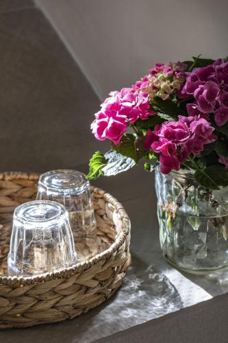 a vase with purple flowers in it next to a basket at Gallicantu Stazzo Retreat in Luogosanto