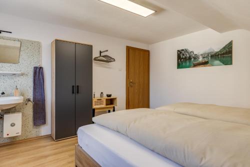 a white bedroom with a bed and a sink at Seeperle Lochau - Der See ruft! in Lochau