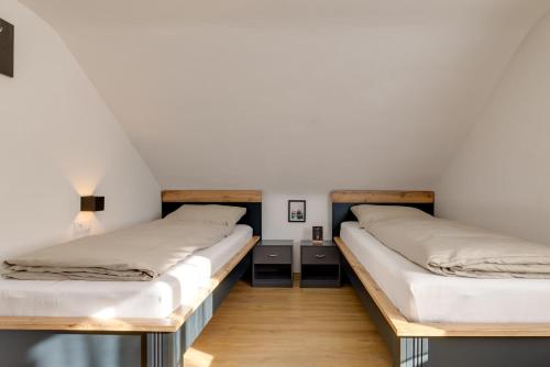two beds in a room with white walls and wooden floors at Seeperle Lochau - Der See ruft! in Lochau