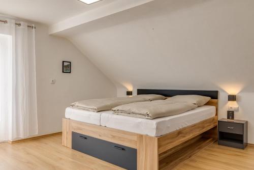 a bedroom with a bed with white walls and wood floors at Seeperle Lochau - Der See ruft! in Lochau
