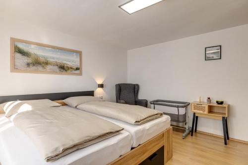 two beds in a room with a desk and a chair at Seeperle Lochau - Der See ruft! in Lochau