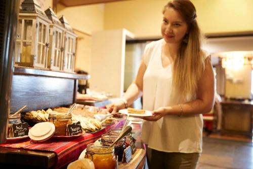 a woman holding a plate of food in a kitchen at Almacruz Hotel y Centro de Convenciones (Ex Galerías) in Santiago