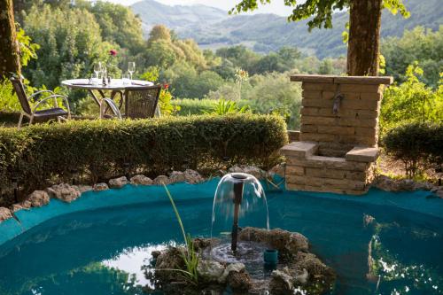 a swimming pool with a fountain and a table at Hotel Les Mésanges in Saint-Martin-dʼUriage