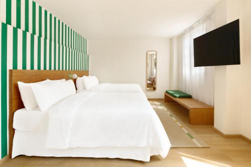 a bedroom with a white bed and a flat screen tv at Hotel Parián in Mexico City