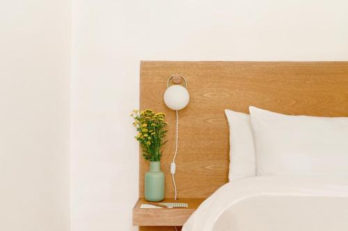 a bed with a lamp and a vase with flowers on a table at Hotel Parián in Mexico City
