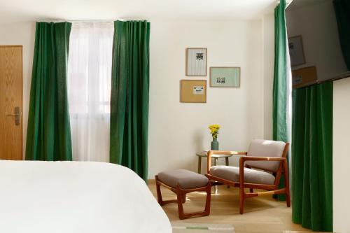 a bedroom with green curtains and a bed and chairs at Hotel Parián in Mexico City