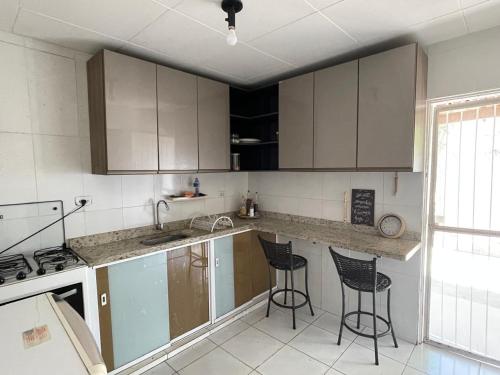 Una cocina con encimera y dos taburetes de bar. en Casa De Temporada Mandacaru, en Piranhas