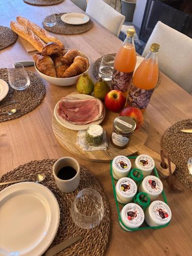 a wooden table with food and juice and bread at Le verger de Paulin in Yvoir