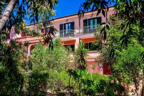 a pink building with trees in front of it at Residence with swimming-pool in Sos Alinos in Orosei
