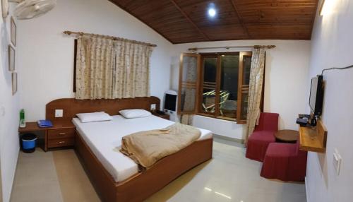 a bedroom with a bed and a television in it at Experto The Greens in Nainital