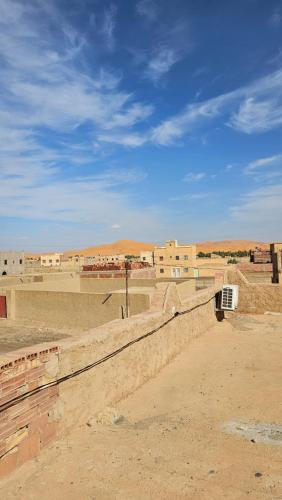 a view of a desert with buildings in the background at Nomad Merzouga Desert House in Hassilabied