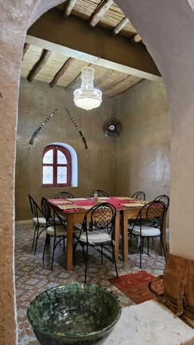 a dining room with a wooden table and chairs at Nomad Merzouga Desert House in Hassilabied