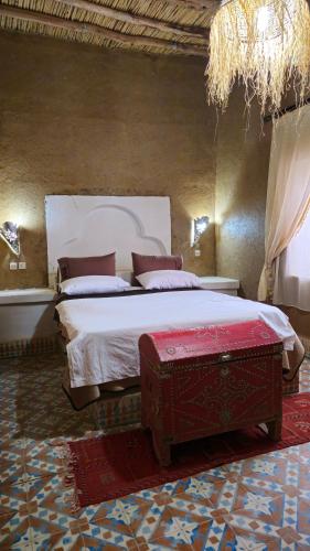 a bedroom with a large bed with a red trunk at Nomad Merzouga Desert House in Hassilabied