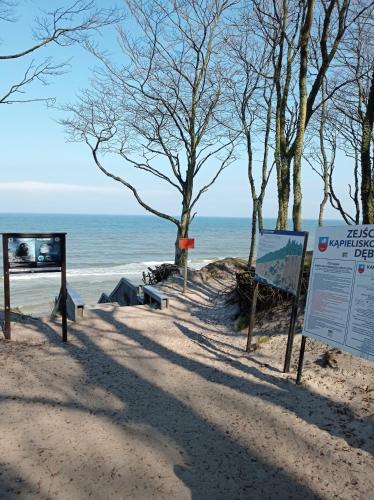 a sign on a beach with the ocean in the background at Leśny Klif in Debina