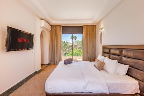 a bedroom with a large white bed and a television at Villa Riad Targa 10 min de GUELIZ Piscine privee in Marrakech