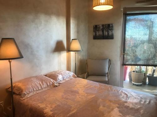 - une chambre avec un lit, deux lampes et une chaise dans l'établissement Appartement parc Marianne espace fitness, à Montpellier