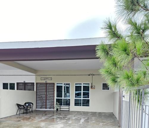 a house with a porch with chairs and palm trees at Syahar Homestay Temerloh in Temerloh