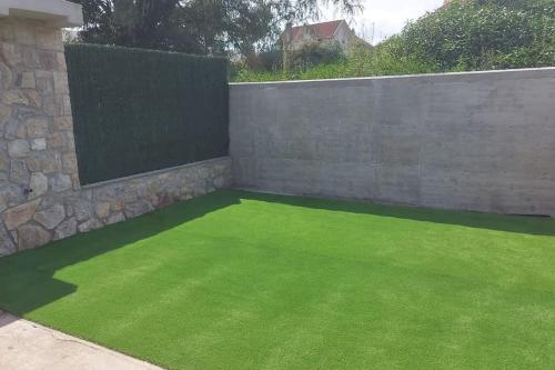 a garden with green grass next to a fence at La Herrería de Somo in Somo