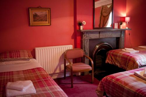 a red room with two beds and a chair and a fireplace at Regent House Hotel - City Centre Hotel in Edinburgh