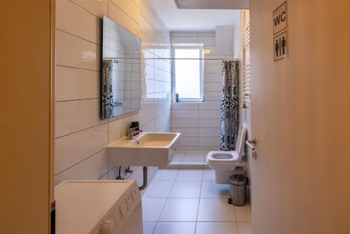 a white bathroom with a sink and a toilet at Sunny & Bright Central in Pristina