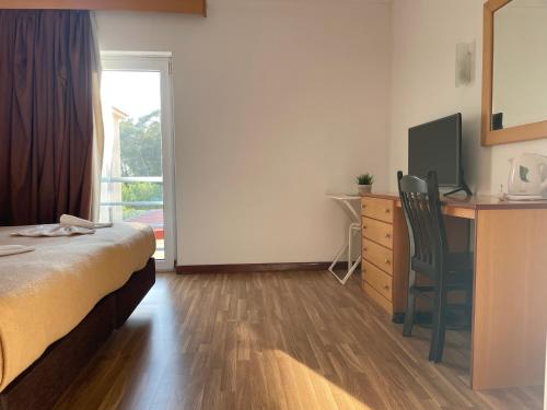 a hotel room with a bed and a desk and a television at Juiceven Studios in Alcabideche