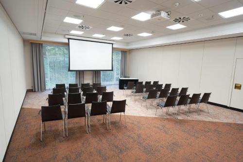a conference room with chairs and a projection screen at Radisson Blu Hotel Dortmund in Dortmund