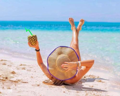 a woman laying on the beach with a drink at Davinci Beach Resort in Hurghada